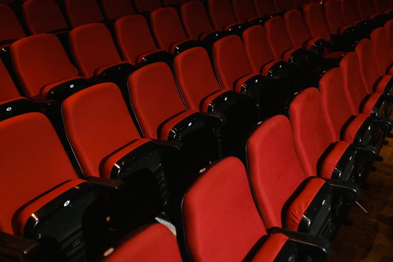 Empty rows of red seating in a modern indoor cinema or auditorium, ready for use.